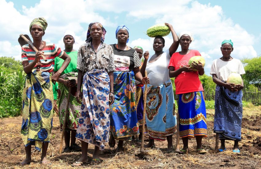 Group of female farmers in the African growth corridors, holding melons and farming equipment.